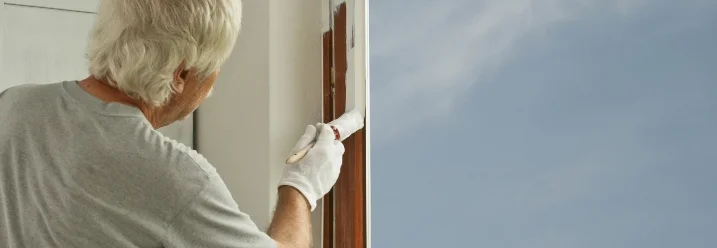 Person streicht Fensterrahmen mit Pinsel